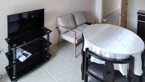A living room with a TV, sofa, and dining table.