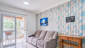 A living room with a sofa, a wooden side table, and a picture of a beach scene.