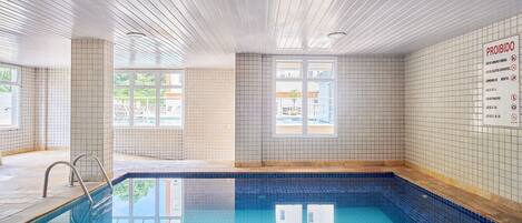 Una piscina al aire libre, sombrillas, sillones reclinables de piscina