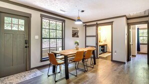 A dining area with a wooden table and chairs, large windows, and a door leading to another room. - Secluded Mountain Retreat: 30 Mi to Asheville! (Old Fort)