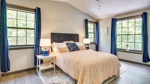 A bedroom with a large bed, two bedside tables with lamps, a ceiling fan, and large windows with blue curtains. - Secluded Mountain Retreat: 30 Mi to Asheville! (Old Fort)