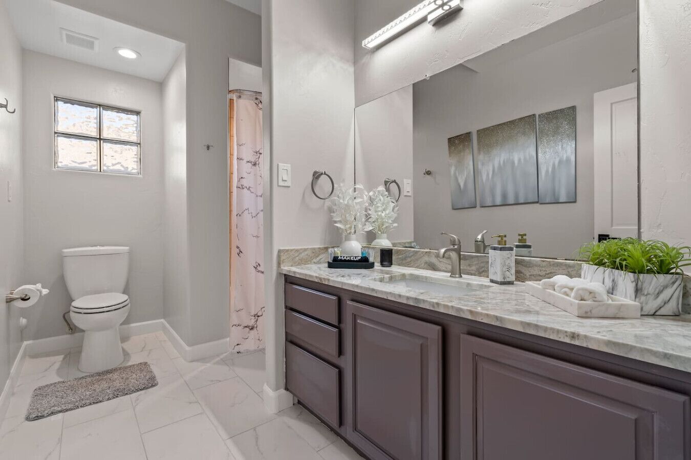 A modern bathroom with a toilet, vanity, and a shower curtain.