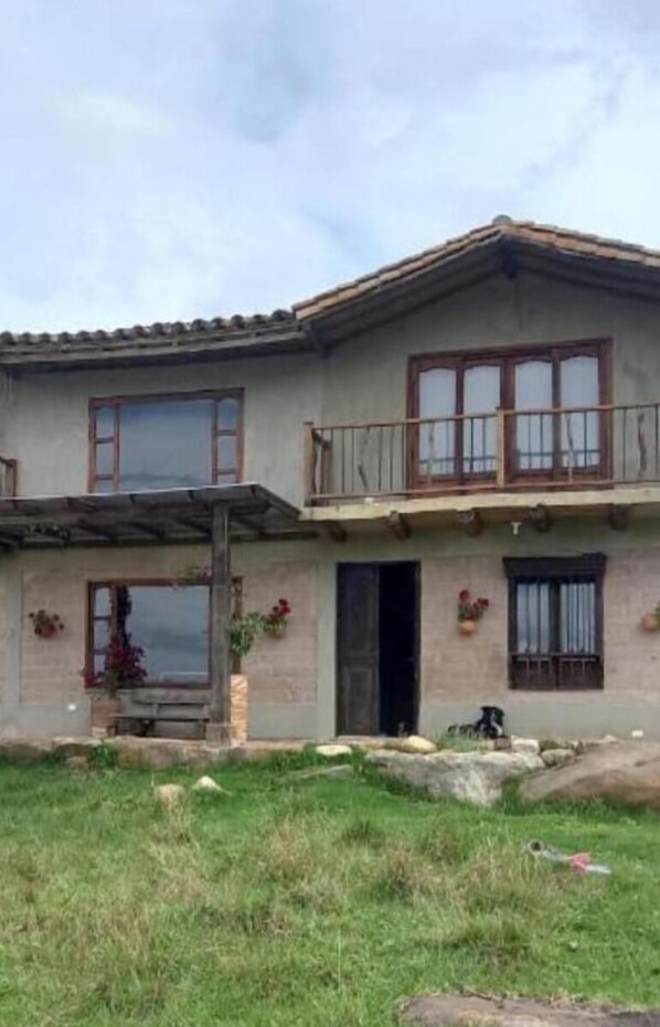 Een huis met twee verdiepingen, een balkon, grote ramen en een gazon.