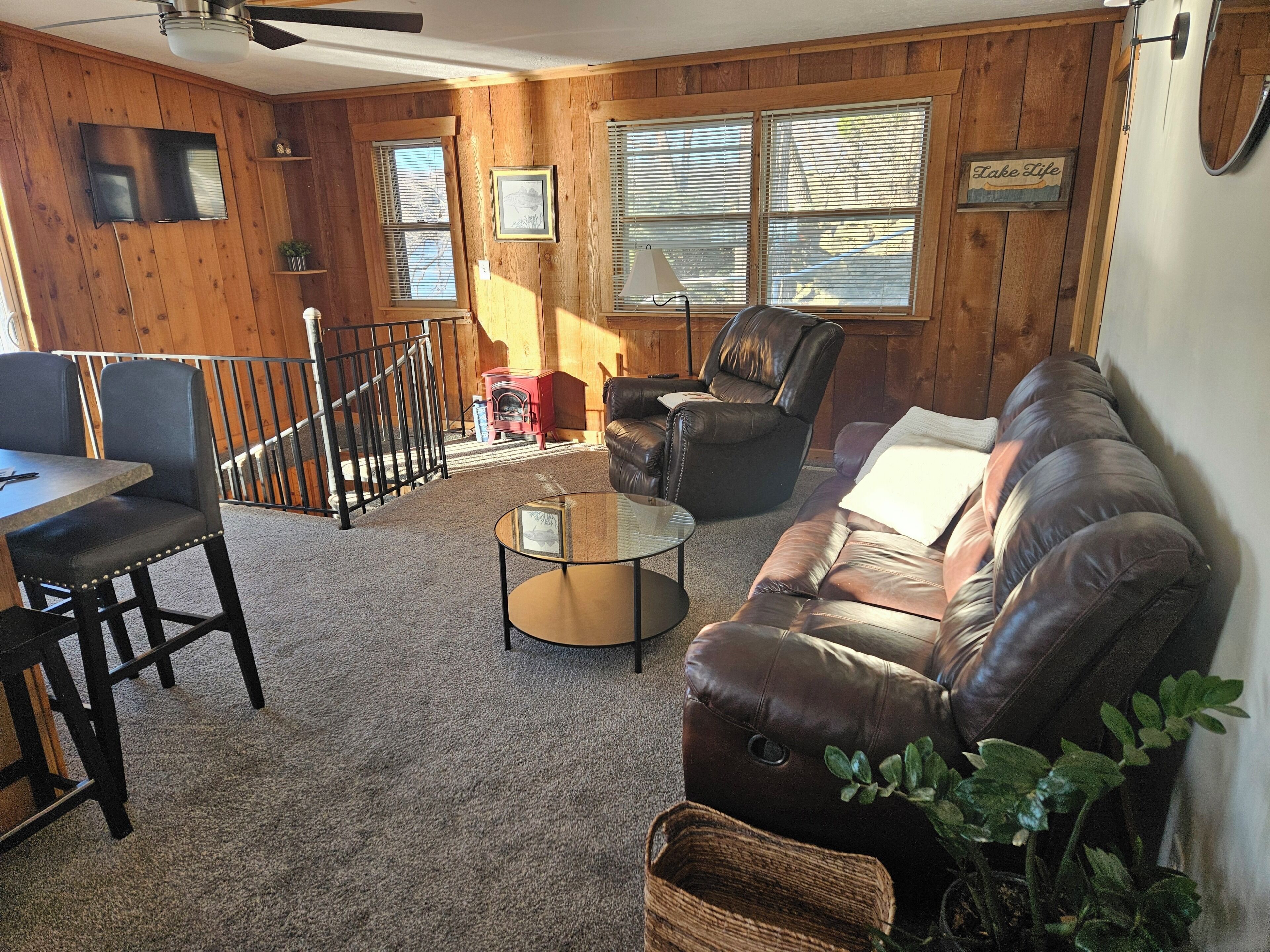 A living room with a leather sofa, a glass coffee table, a fireplace, and a TV mounted on the wall.