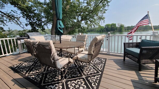 Une terrasse dotée de meubles en osier, d’un barbecue et d’un drapeau américain.