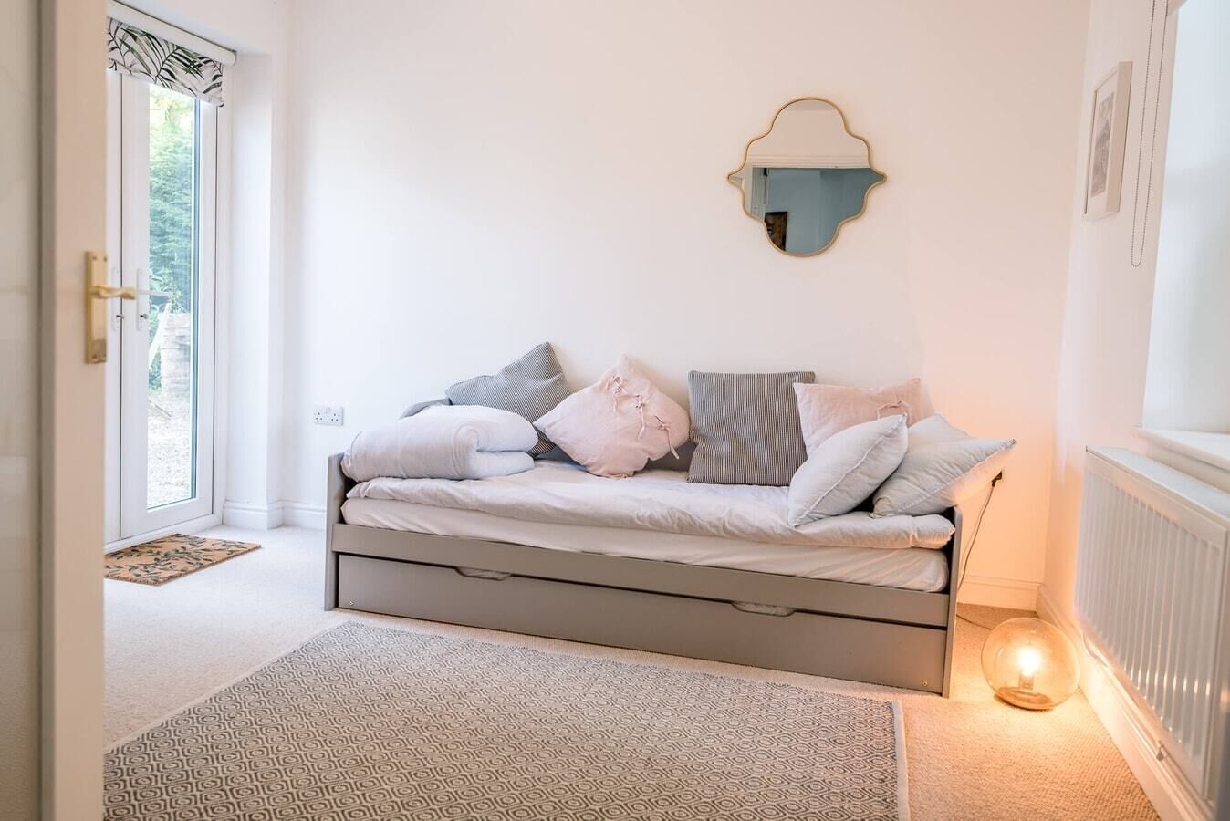 A cozy room with a bed, a wall-mounted lamp, and a door leading outside.