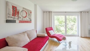 A modern living room with a red sofa, a red armchair, and a white coffee table. - Traum-ferienwohnung Alpenblick, 75 qm, Balkon und Bergblick (Bad Aibling)