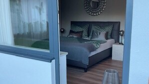Un dormitorio con una cama, una mesita de noche, una lámpara y un espejo en la pared.