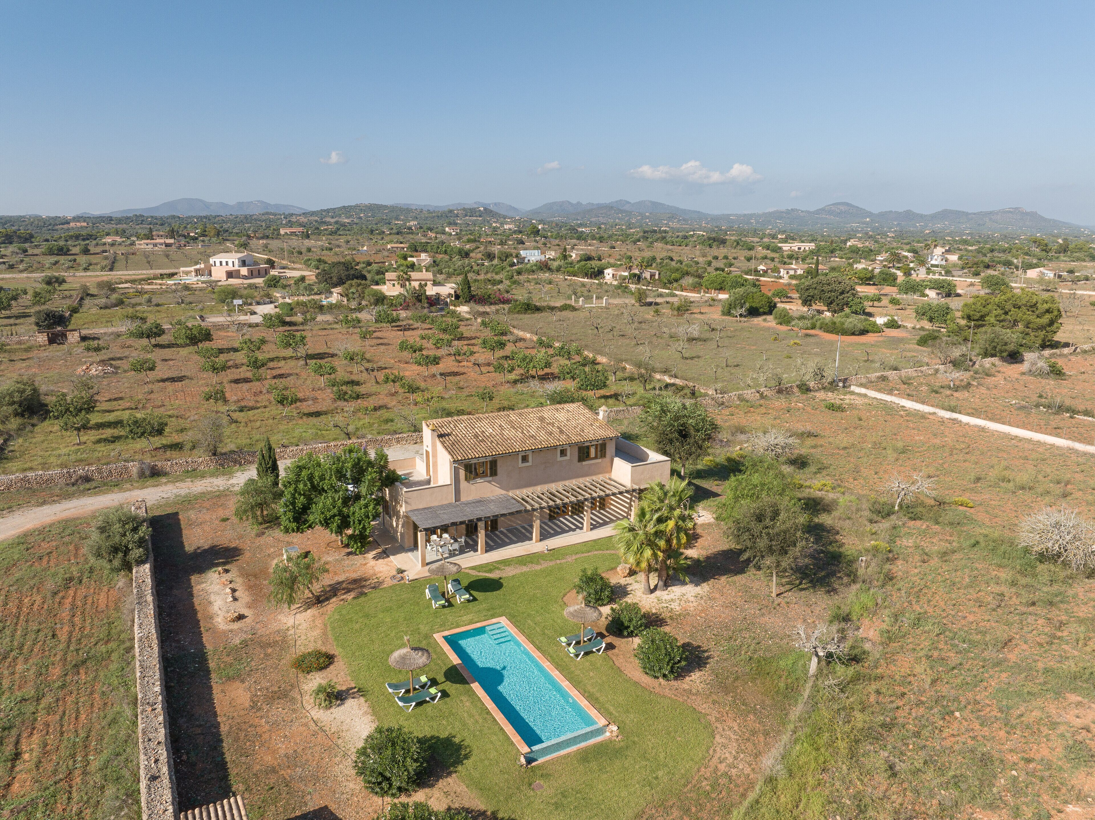Una villa con piscina, rodeada de un jardín y vistas al campo.