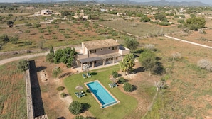 Une villa avec piscine, entourée d’un jardin et offrant une vue sur la campagne.