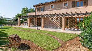 Un bâtiment à deux étages doté d’un patio couvert, d’un chemin en pierre et d’une pelouse bien entretenue.