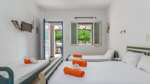 A hotel room with two single beds, a double bed, a TV, a window with an open shutter, and a view of greenery outside. - Holiday Home '9 Perasma Kypri Beach' with Private Terrace, Wi-Fi and Air Conditioning (Kypri)