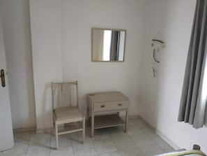 A room with a chair, a small table, a mirror, and a curtain.