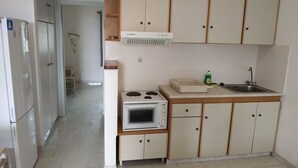 Una cucina compatta con frigorifero, microonde, piano cottura e pensili.