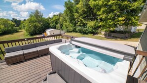A hot tub on a wooden deck with a built-in bench and a small table.