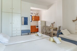 Une chambre avec deux lits, un bureau et un coin cuisine.