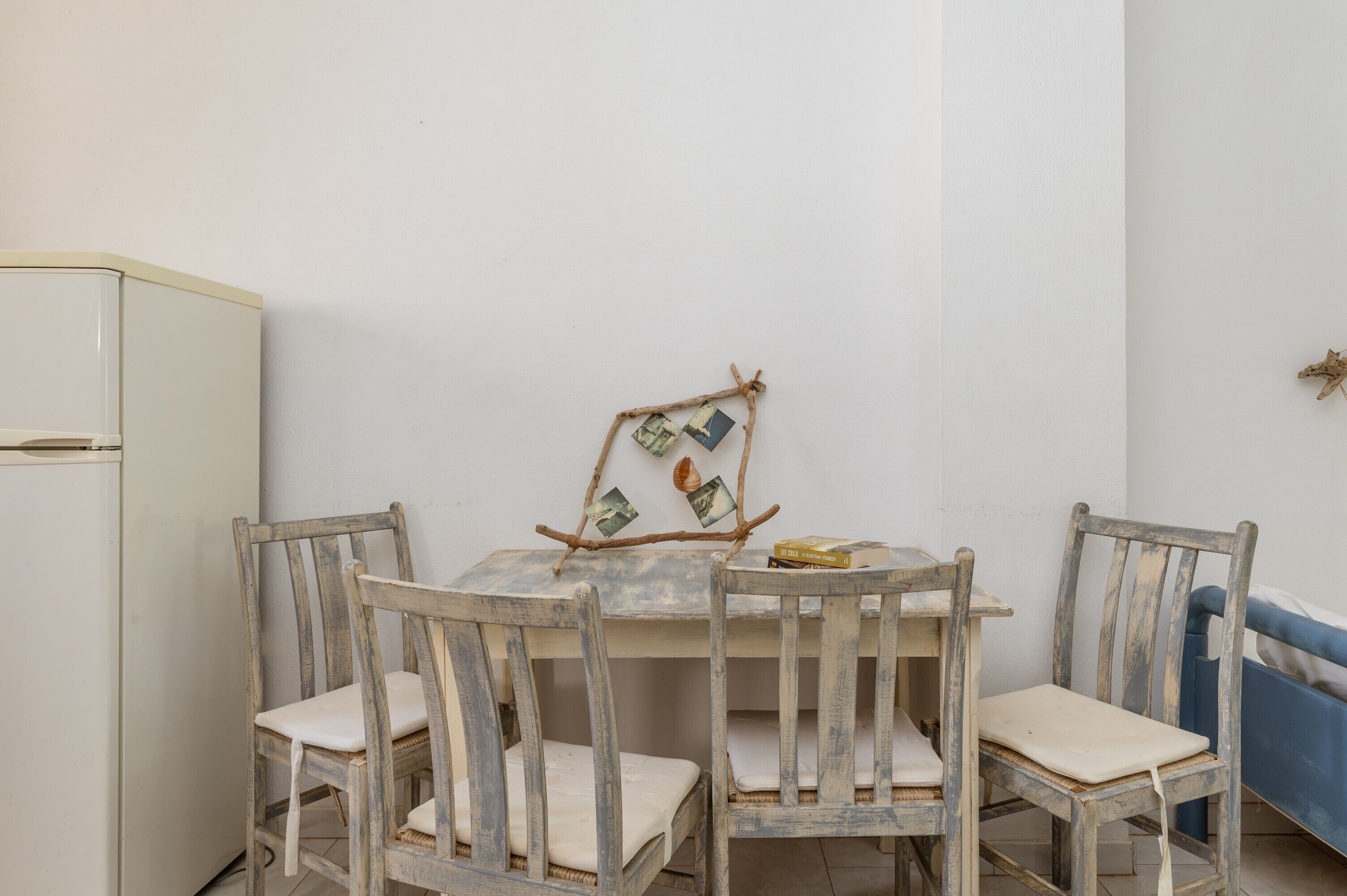 Un petit coin repas avec une table et quatre chaises, un canapé bleu et un réfrigérateur blanc.
