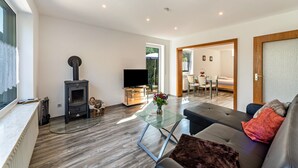 A modern living room with a fireplace, sofa, glass coffee table, and a TV. - Apartment "Burmeister" with Private Terrace & Wi-Fi (Nittenau)