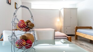 A metal fruit basket on a glass table in a room with a bed, a wardrobe, and a window. - Apartment "Burmeister" with Private Terrace & Wi-Fi (Nittenau)
