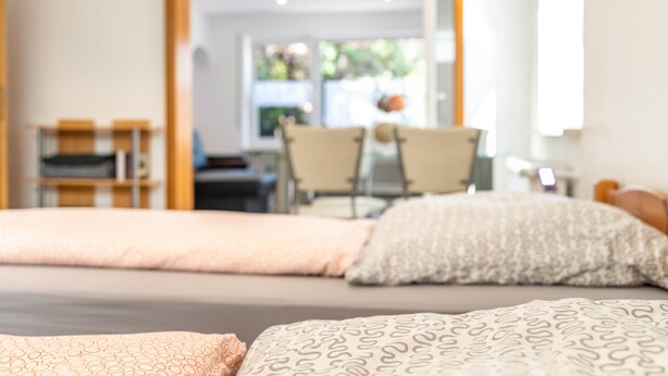 A bedroom with a bed, pillows, a desk, and chairs. - Apartment "Burmeister" with Private Terrace & Wi-Fi (Nittenau)