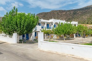 A white building with blue accents, a gated entrance, and a mountainous backdrop.