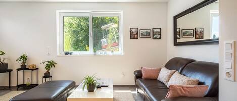Una sala de estar moderna con un sofá de cuero, una mesa de centro y un ventanal con vistas a la vegetación.