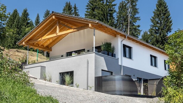 Une maison moderne à deux étages, dotée d’un toit en pente, de grandes fenêtres et d’un balcon.