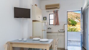 A compact kitchen with a dining table, chairs, a TV, and a view of the outdoors. - Holiday Home '1b Kypri Seaview Perasma Studio' with Sea View, Wi-Fi and Air Conditioning (Kypri)