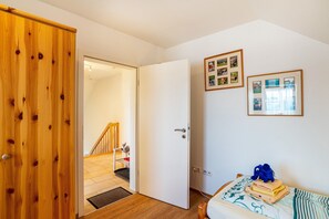Een slaapkamer met een houten deur, een bed met een bed met een patroon en een muur met ingelijste foto's.