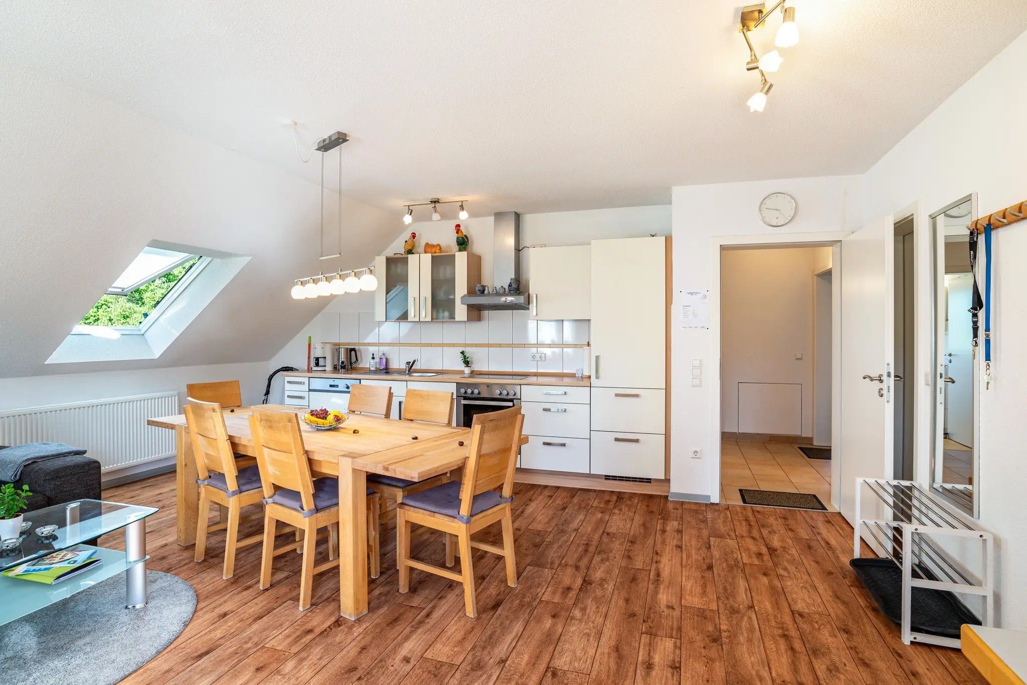 Una cocina moderna con armarios de madera, una mesa de comedor con sillas y un tragaluz.