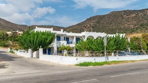 A coastal building with white walls and blue accents, surrounded by greenery and hills. - Holiday Home '3 Kypri Seaview Perasma Studio' with Sea View, Wi-Fi and Air Conditioning (Kypri)