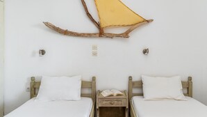 A room with two wooden beds, a small wooden nightstand with an open book, and a wall-mounted branch decoration. - Holiday Home '3 Kypri Seaview Perasma Studio' with Sea View, Wi-Fi and Air Conditioning (Kypri)