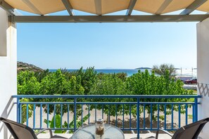 Un balcón con vista al mar, una mesa con un tarro de vidrio y una barandilla azul.