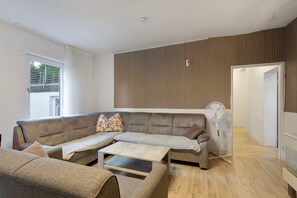 Una sala moderna con un sofá modular, una mesa de centro y un ventilador de pie.