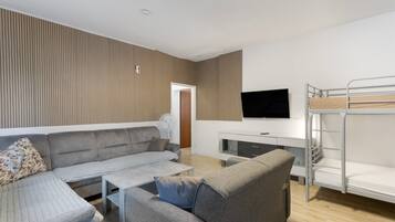 En moderne stue med sofa, sofabord og køjeseng.