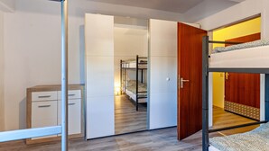Une petite pièce comprenant un lit superposé, une armoire et un bureau.