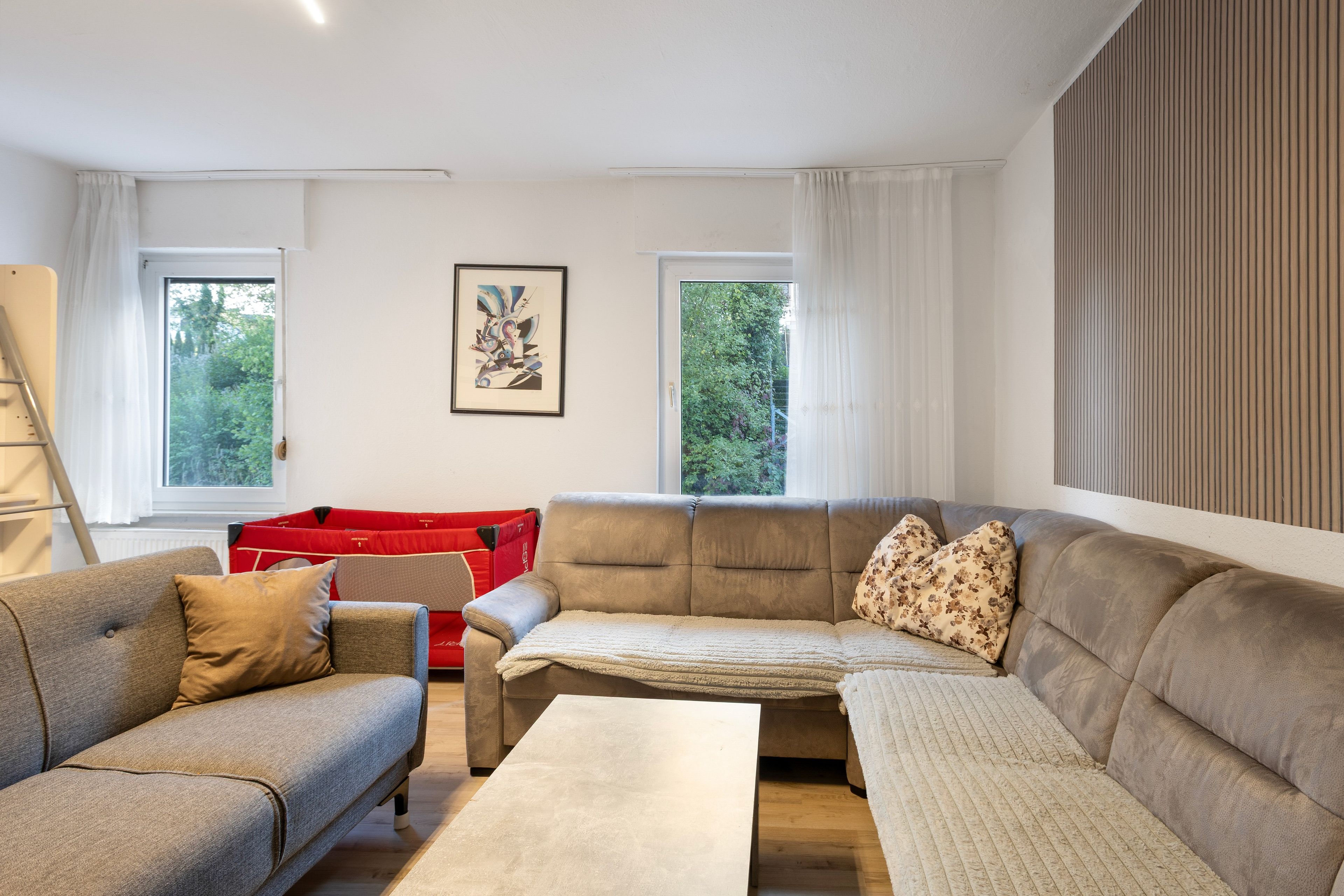 Una sala de estar moderna con un conjunto de sofá, un mueble de almacenamiento rojo y una obra de arte enmarcada en la pared.
