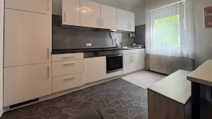 Une cuisine moderne avec des meubles blancs, un plan de travail noir et un sol à motifs.