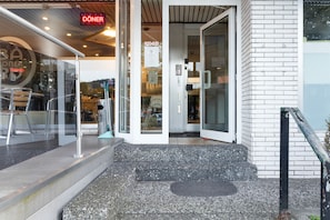 L'ingresso di un edificio con una porta in vetro, una scala in metallo e un cartello sopra la porta.