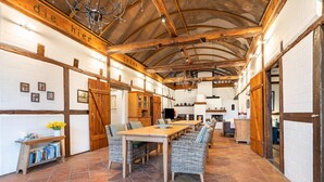 Un intérieur rustique avec une longue table à manger, des chaises en osier et un sol carrelé.