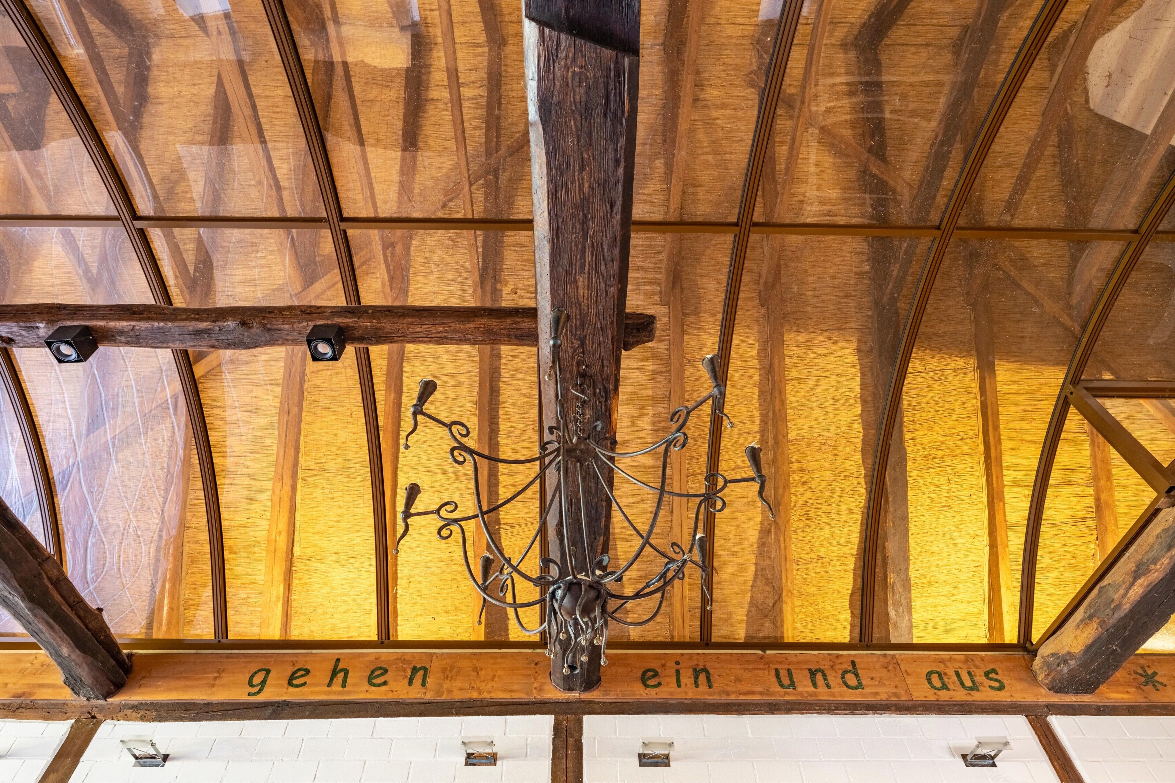 A wooden ceiling with a chandelier and a sign with text.