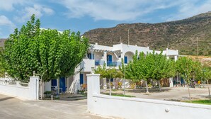 A white building with blue accents, a gated entrance, and a mountainous backdrop.