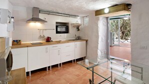 A kitchen with white cabinets, a microwave, a wooden countertop, and a glass table.
