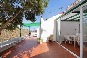 Un patio con una mesa, sillas, un banco y una planta en maceta.