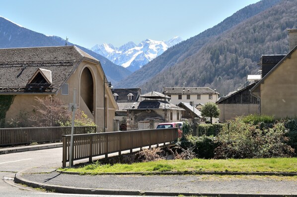 A town with a prominent arch bridge, buildings with traditional architecture, and a mountain backdrop.