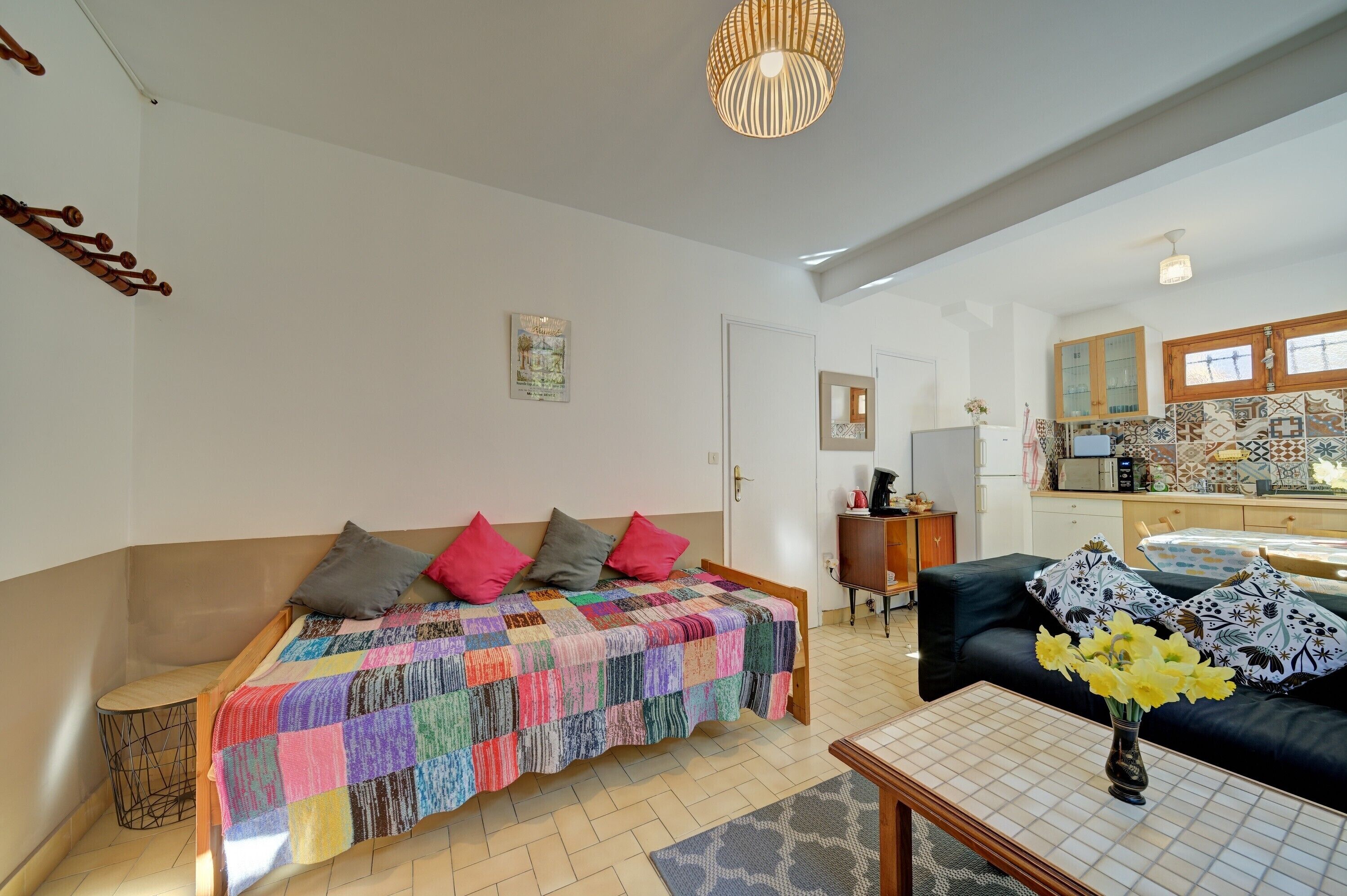 Un salon avec un canapé, une table basse et un lit recouvert d’une couverture aux couleurs vives.