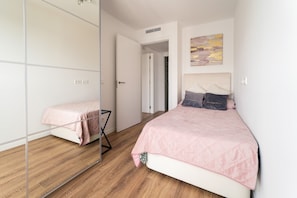 Un dormitorio con cama, espejo, armario y puerta que da a otra habitación.
