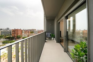 A balcony with a city view, a chair, and a potted plant. - Vacation Apartment "Sunsets & Pool in Barcelona" with Balcony, Shared Pool & Wi-Fi (Cornellà de Llobregat)