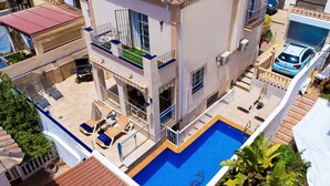 Un immeuble à plusieurs étages doté d’une piscine, d’un espace extérieur aménagé et d’une voiture garée à proximité.