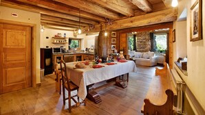 Un interno rustico in legno con un tavolo da pranzo, sedie, un angolo cottura e una zona salotto accogliente.
